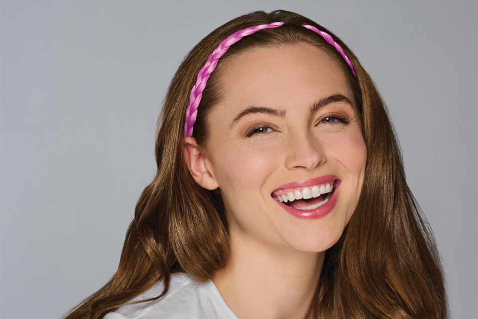 A white woman wearing a pink braided headband