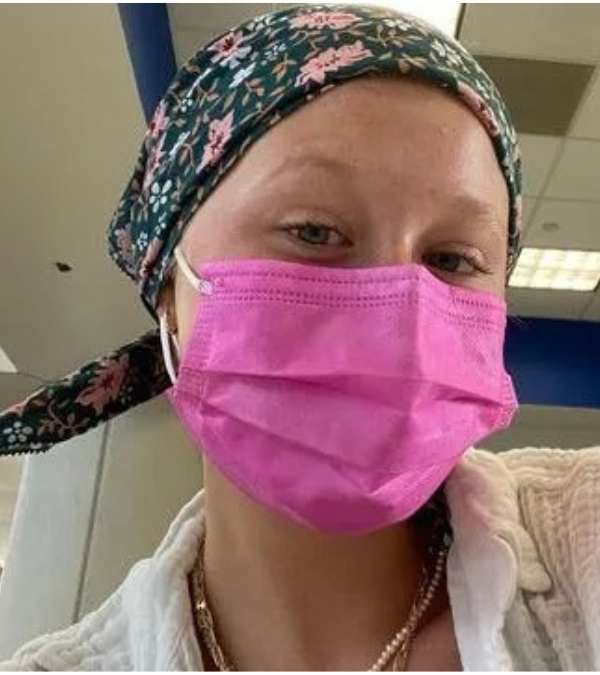 Actress Mirand McKeon taking a selfie wearing a hot-pink mask and hair scarf during chemotherapy for breast cancer.