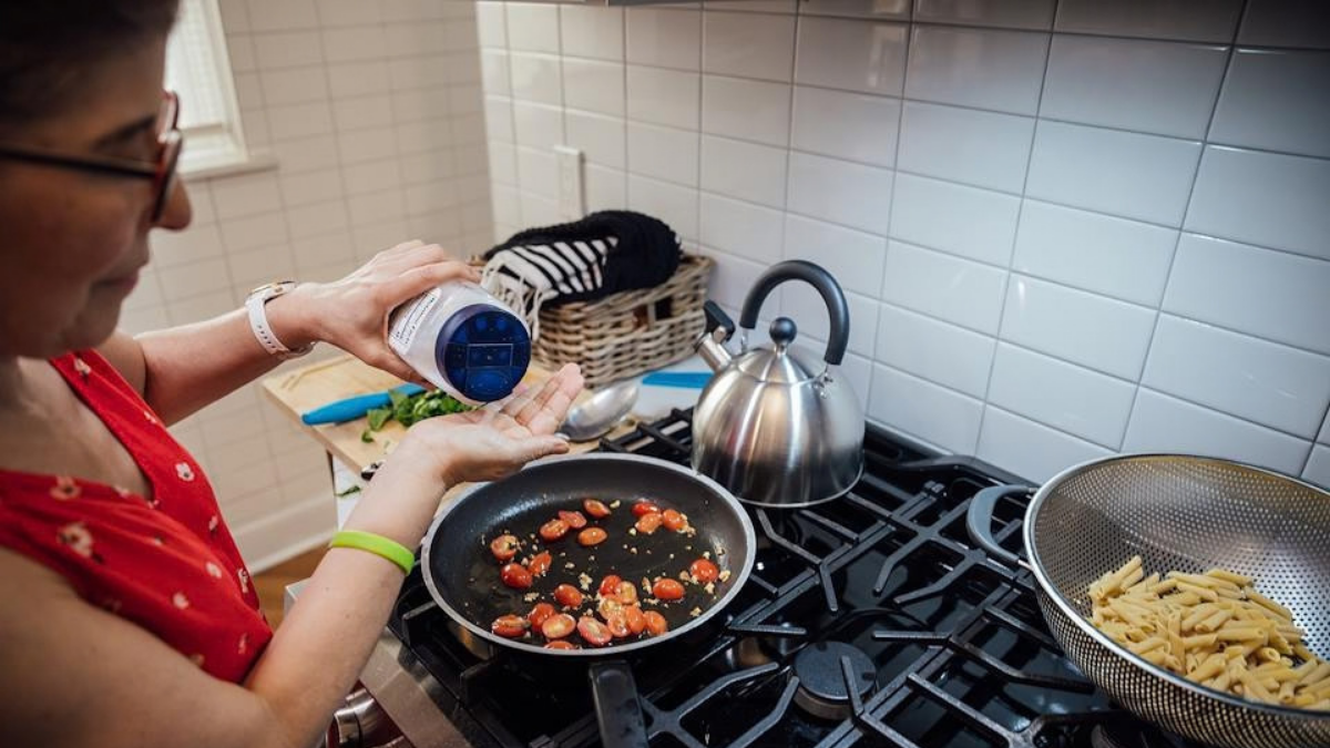 A woman cooking vegetables and pasta.