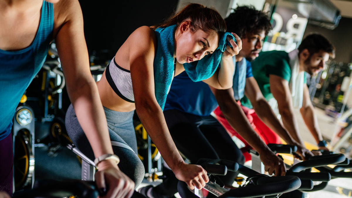 A diverse group of adults sweating in a cycling class