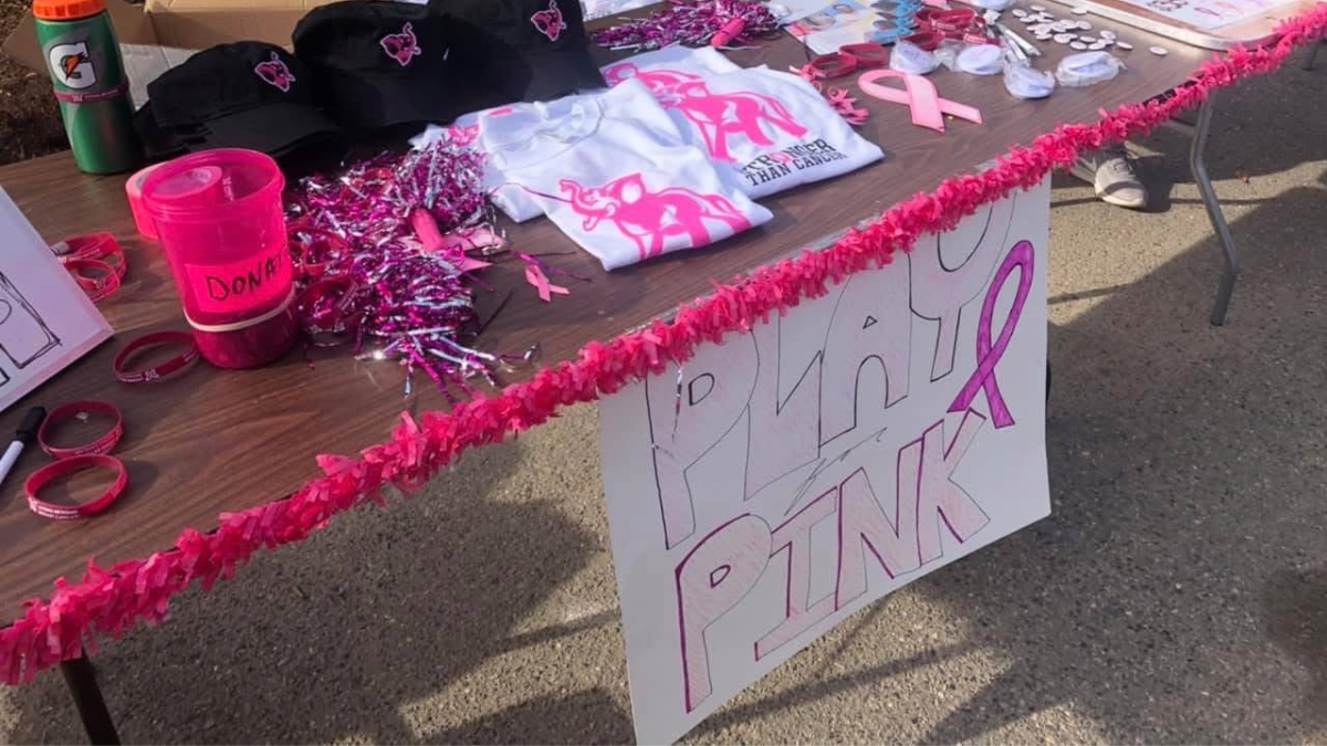 Living Beyond Breast Cancer merchandise and Play 4 Pink t-shirts on a table at the Play for Pink event at Tufts University.