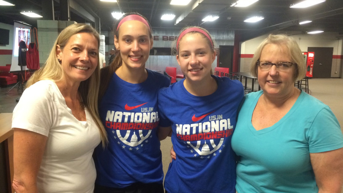 Lilly Bolen and a teammate pose with their mothers wearing basketball club team t-shirts.