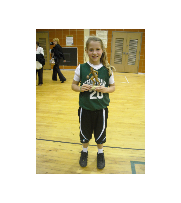 A much younger Lilly Bolen stands in her basketball uniform holding a trophy.