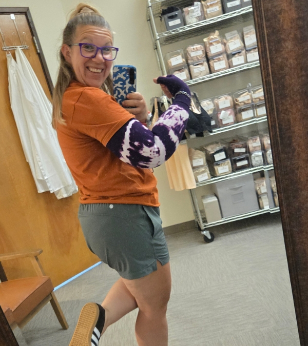 Meg Graves shows off her lymphedema-sleeved arm proudly as she enters a supply closet.